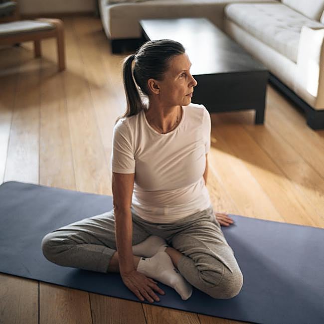 Mujer practicando yoga en casa.