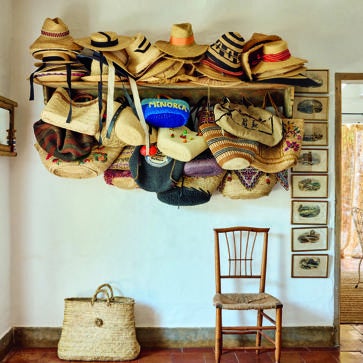 Imagen secundaria 1 - Arriba, rincón de la cocina, con azulejos antiguos recuperados de Antic Alaior, lámpara en suspensión portuguesa, de Candelabro, y antigua pìla de piedra. A la derecha, detalle de la mesa con vajilla de insectos de Sena Cifuentes y vasos de vidrio pintados a mano de Agua Clara. A la izquierda, el perchero de la entrada con toda la impresionante colección de sombreros y cestas de madre e hija.