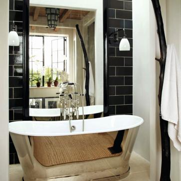 Imagen secundaria 1 - Arriba, la habitación principal de la casa, con cortinas que cubren las paredes del techo al suelo, a modo de tapices, proporcionándole una atmósfera recogida y romántica. Abajo a la izquierda el baño, con azulejos marroquíes, donde destaca una bañera exenta. A la derecha, vista del recibidor y de la escalera, que en la reforma se movió de sitio para hacer más proporcionada la entrada.