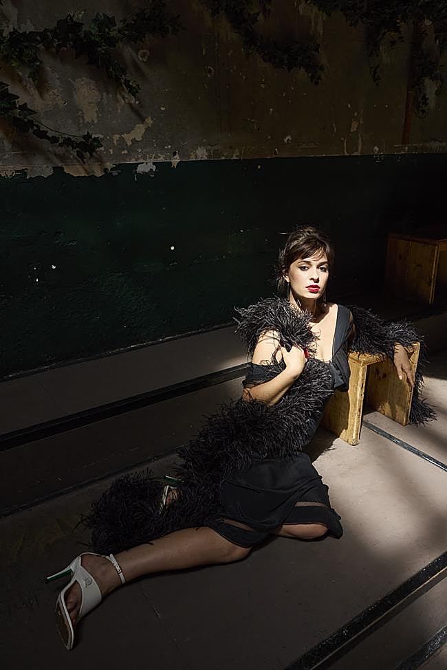 Dora posando con vestido lencero de RABANNE, boa de TOT-HOM, pendientes de PARFOIS, anillo de KIWIPOMELO, y sandalias de TOMY HILFIGER.