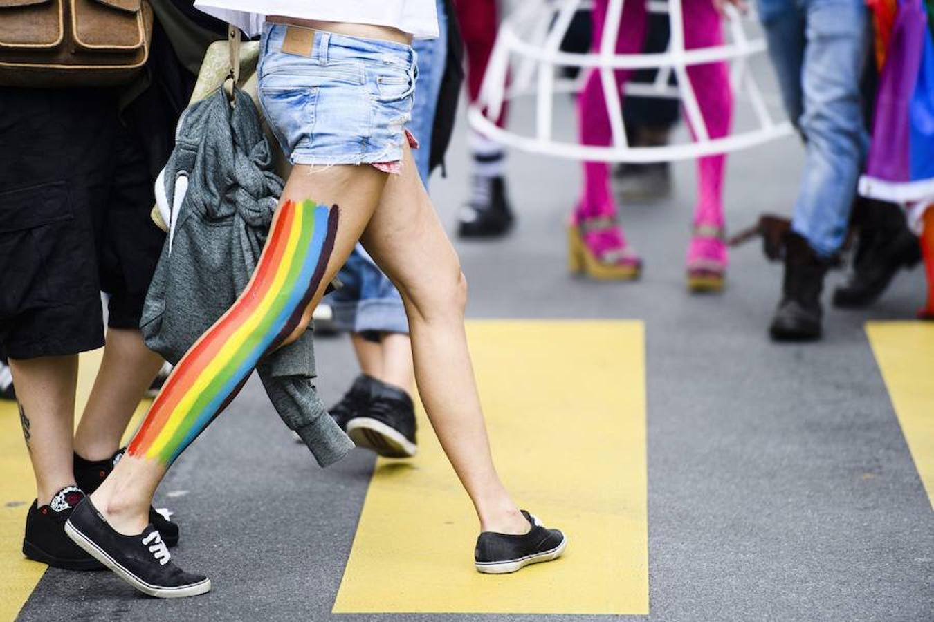 Una transeunte con la bandera color arcoiris pintada en la pierna cruza la calle durante la Marcha del Orgullo Gay en Suiza.