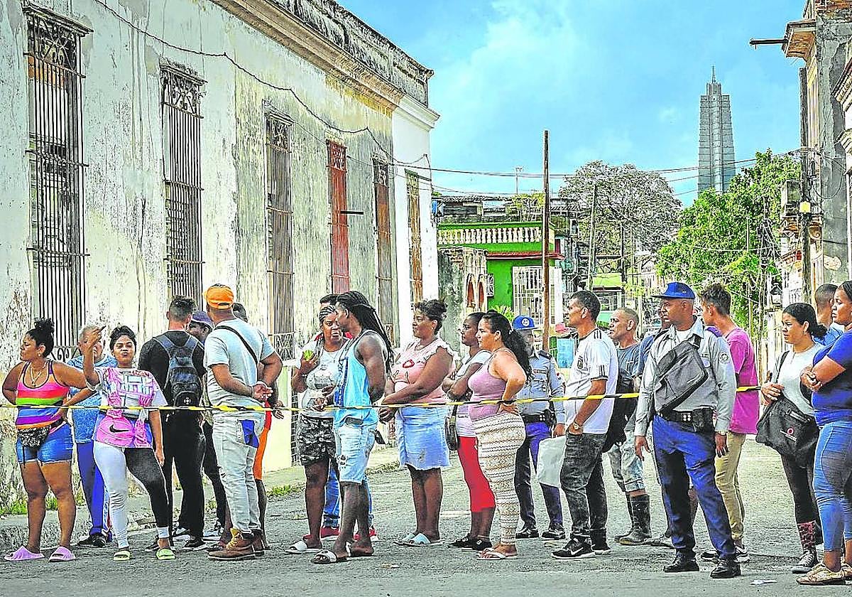 Una fila de cubanos siguen los trabajos de reparación de los daños ocasionados por el huracán 'Ian' en la localidad de El Cerro