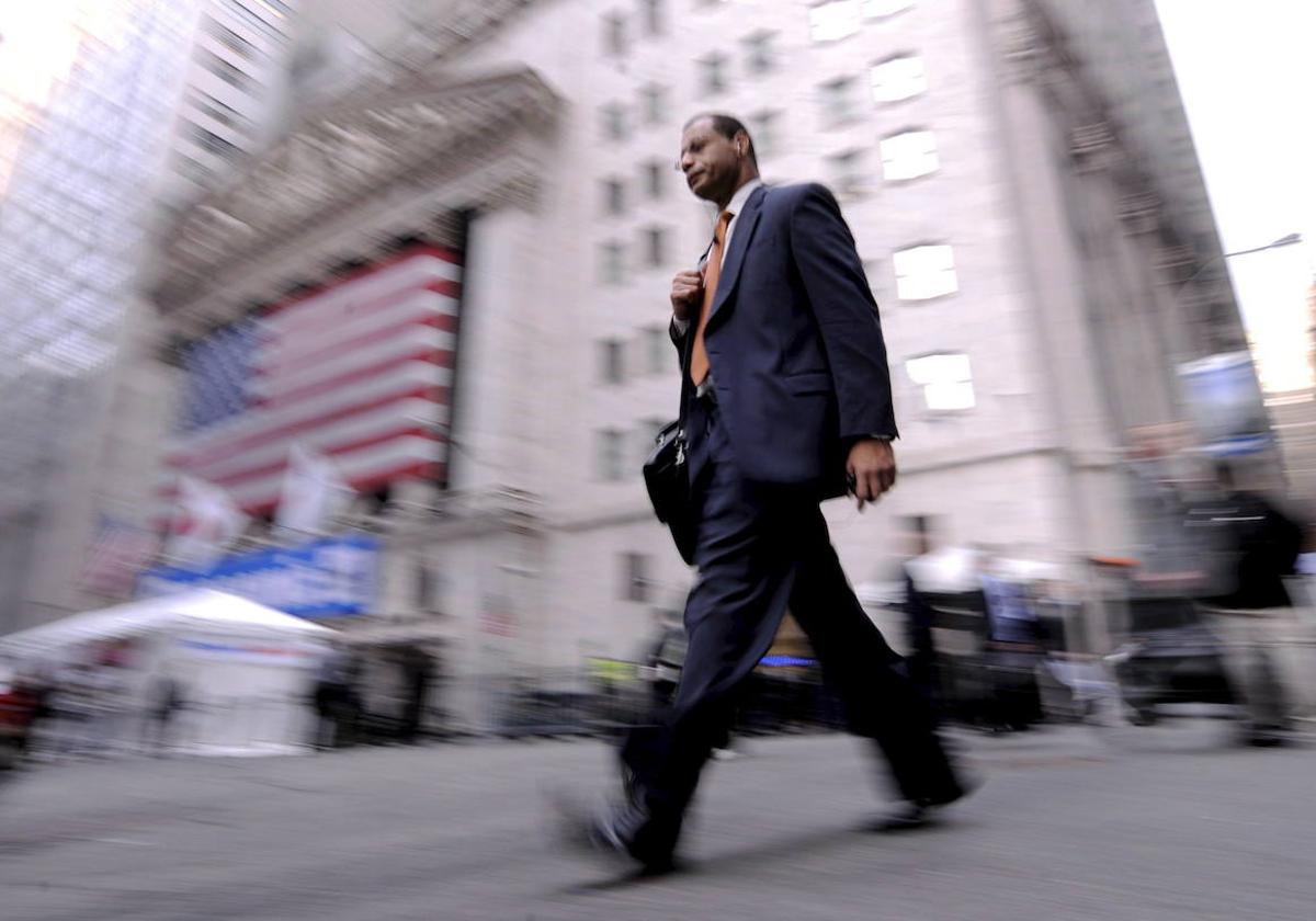 Un hombre camina junto a la fachada de Wall Streeet