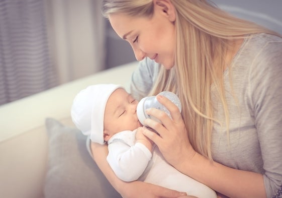 Una madre da leche de fórmula a su hijo