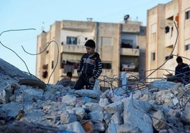 Niño sobre ruinas tras el terremoto en Siria.