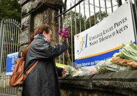 Una mujer coloca un ramo de flores en la entrada del centro en que fue acuchillada mortalmente el miércoles la profeosra Agnès Lassalle