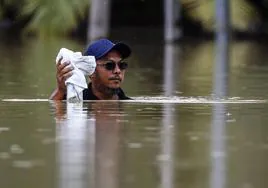 Un hombre camina en un área inundada mientras continúa la lluvia sobre Yong Peng, en Johor.