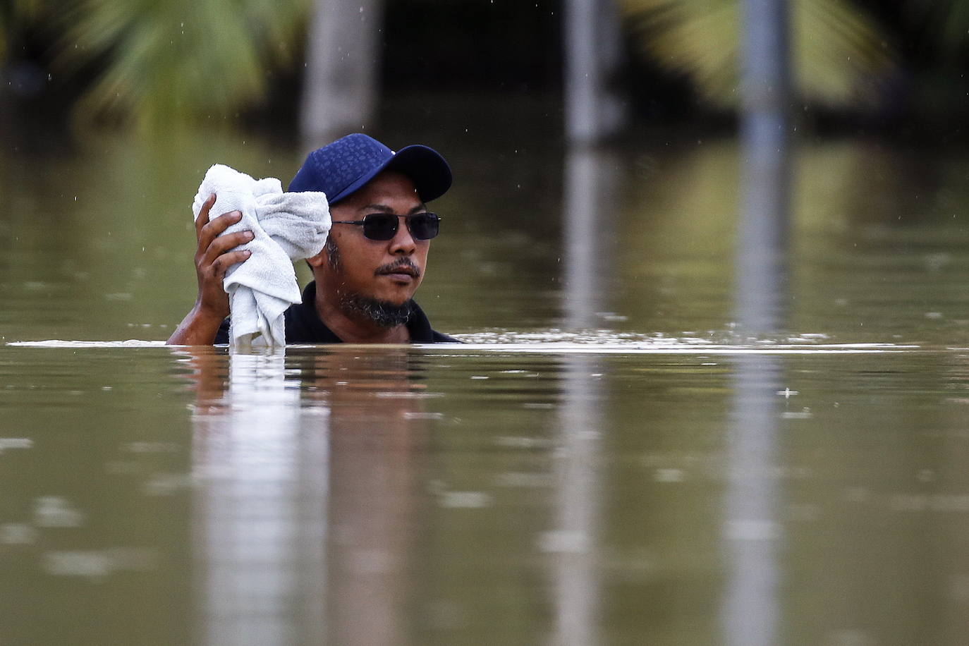 Un hombre camina en un área inundada mientras continúa la lluvia sobre Yong Peng, en Johor.