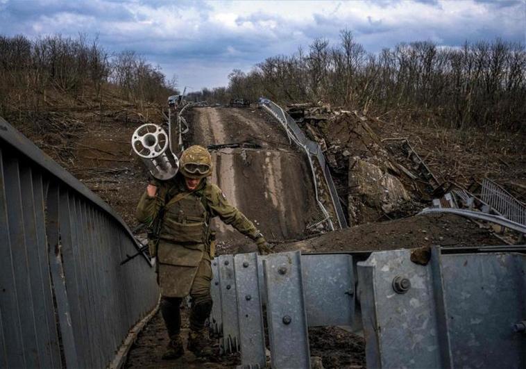 Un soldado ucraniano carga con un lanzamisiles al atravesar uno de los puentes de acceso de Bajmut destruido por los bombardeos rusos.