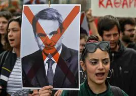 Una mujer exhibe una pancarta en contra del primer ministro griego, Kyriakos Mitsotakis, durante una protesta en Atenas.