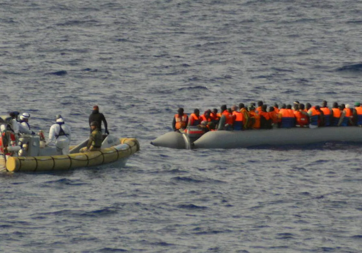 Una lancha de la Armada italiana se aproximan a un bote neumático lleno de inmigrantes cerca de la costa de Lampedusa