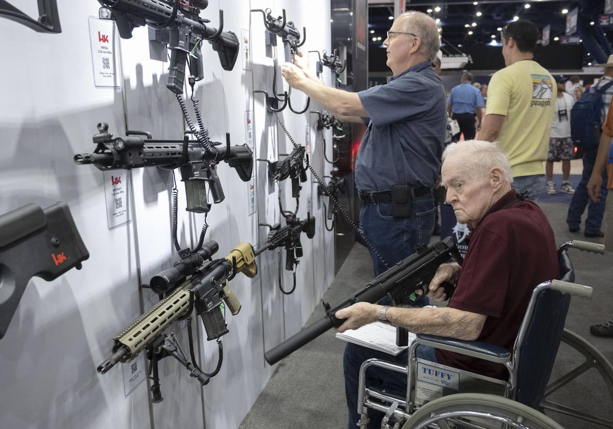 Dos visitantes inspeccionan armas de fuego durante una feria comercial de la Asociación Nacional del Rifle de Estados Unidos