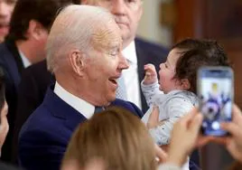 Joe Biden, que viajará este viernes a Ottawa, coge en brazos a un niño en un acto en Washington.