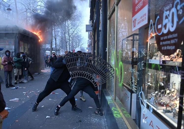 Imagen principal - Dos radicales destrozan un escaparate durante las refriegas que tuvieron lugar en una jornada donde se repitieron los incendios y disturbios en varias ciudades francesas.