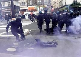 Un policía protege con su escudo a un compañero.