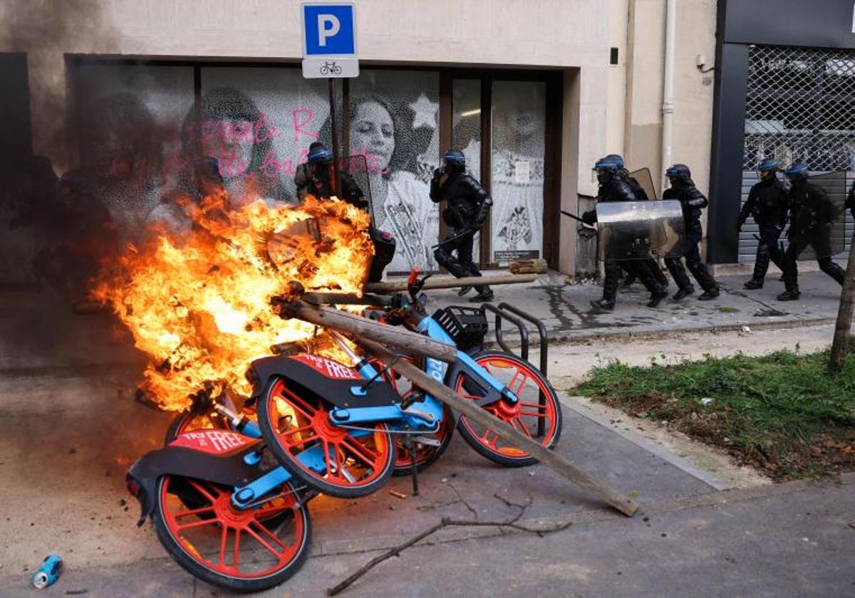 La Policía antidisturbios en una calle de París en la que se observan bicicletas de alquiler en llamas.