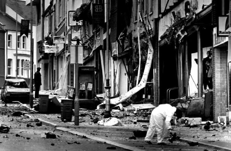 Bir polis memurunun 1992'de Belfast'ta bir arabaya yerleştirilen bombanın kalıntılarını incelediği, İrlanda'daki kurşun yıllarından yinelenen bir görüntü