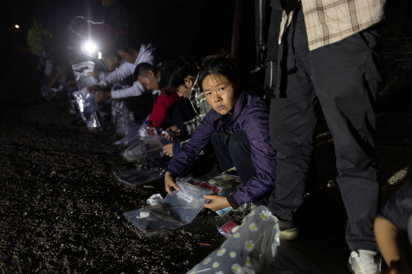 Una mujer migrante de China coloca sus pertenencias en una bolsa de plástico tras ser descubierta cruzando el Río Bravo de manera ilegal