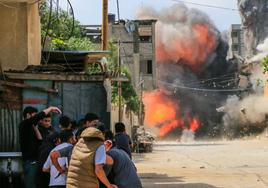 Residentes de Gaza se ponen a cubierto al ser bombardeado este viernes un edificio por el Ejército israelí.