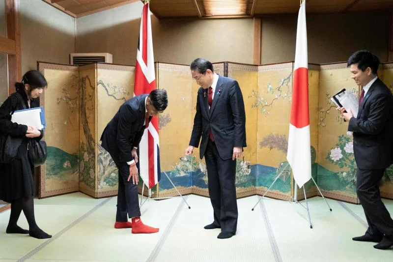 Insólita imagen en la que el primer ministro británico, Rishi Sunak, muestra sus calcetines con el logo del club de béisbol Hiroshima Toyo Carp. a su homólogo japonés, Fumio Kishida, seguidor de este equipo