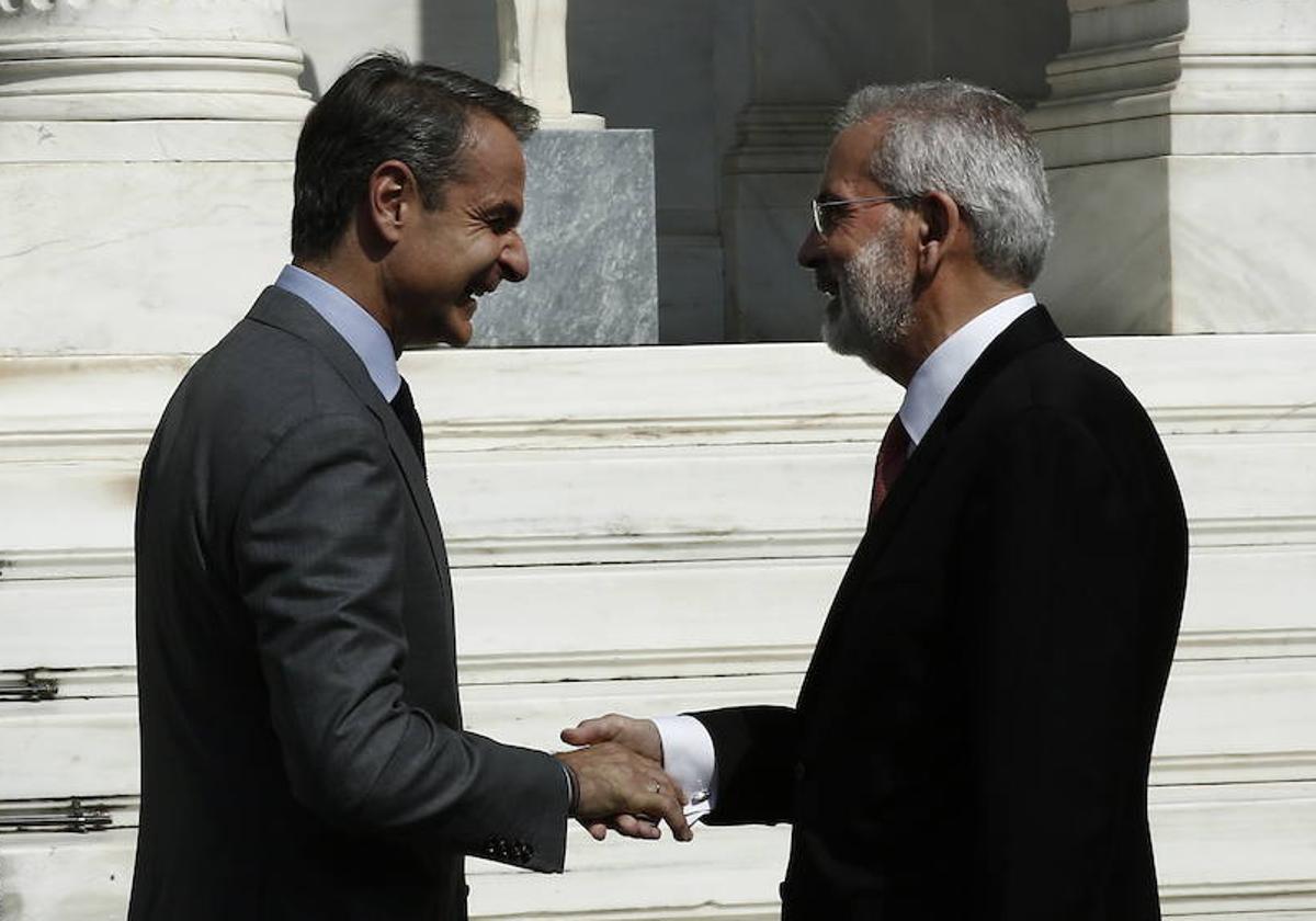 El primer ministro griego saliente, Kyriakos Mitsotakis, saluda al nuevo jefe de Gobierno interino, Ioannis Sarmas, en Atenas