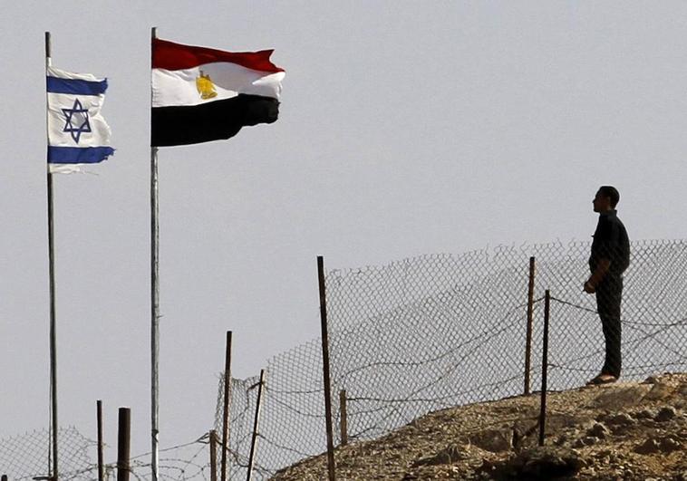 Un soldado egipcio observa las banderas de Egipto y de Israel que ondean en un puesto fronterizo.