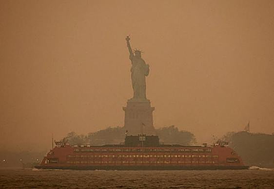 Vista de la estatua de la Libertad con el cielo enrojecido.