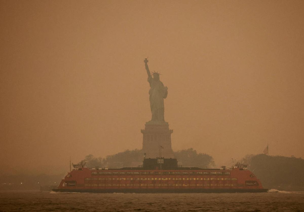 Vista de la estatua de la Libertad con el cielo enrojecido.