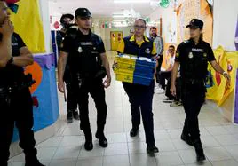 Varios policías escoltan a una trabajadora de Correos hasta la mesa de un colegio electoral de Melilla el 28 de mayo pasado.