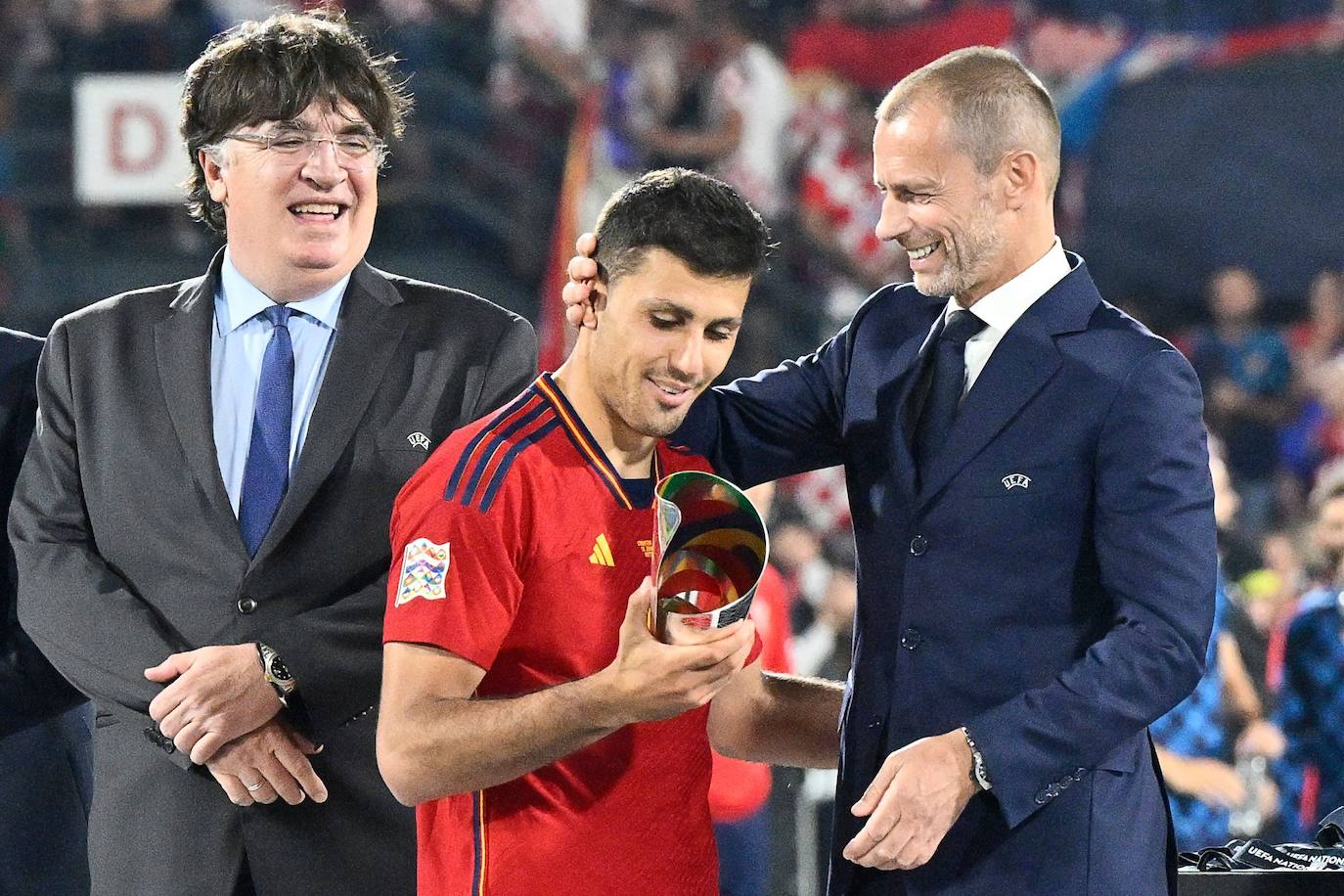 El mediocampista español Rodrigo Hernández (centro) recibe la copa del mejor jugador de la Liga de Naciones de la UEFA de manos del presidente de la UEFA Aleksander Ceferin (derecha) después de ganar el partido de fútbol final de la Liga de Naciones de la UEFA entre Croacia y España. 