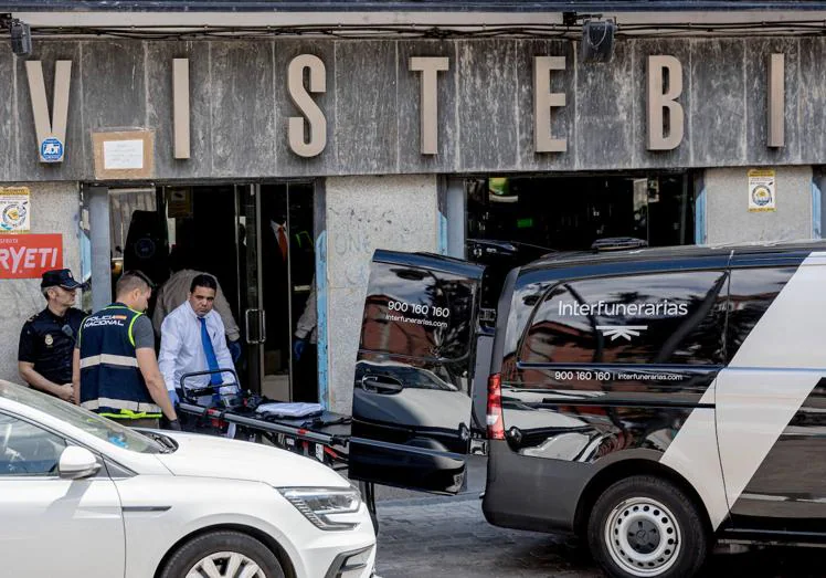 Un trabajador de la empresa Interfunerarias lleva la camilla para trasladar el cuerpo de la mujer apuñalada en su tienda de ropa.