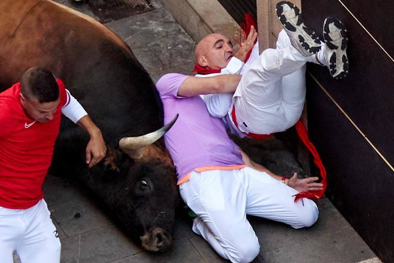 Mozos volteados por un toro, en el tramo la curva de Mercaderes al inicio de Estafeta.