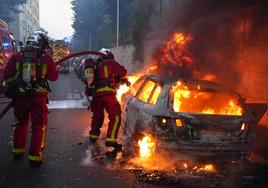 Los bomberos apagan un coche en llamas en París en un suceso registrado en las protestas de hace unos días por la muerte de un joven de 17 años.