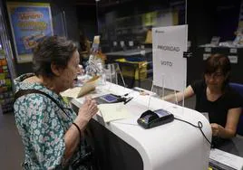 Una mujer entrega la documentación para ejercer el voto por correo en una oficina de Madrid .