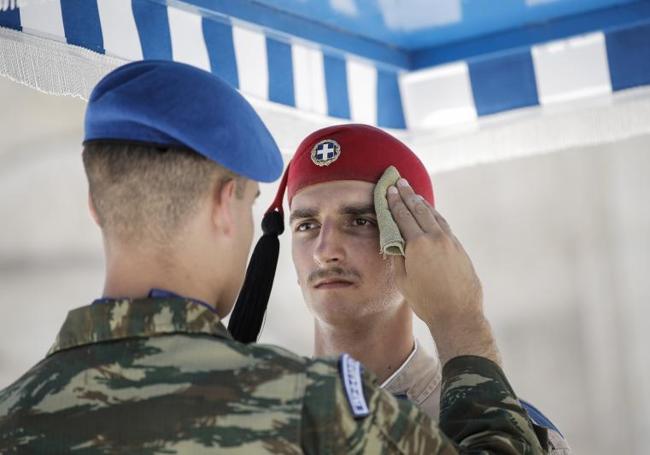 Un oficial limpia la cara de un guardia presidencial de Grecia, en cuya capital, Atenas, los termómetros marcaron los 40 grados.