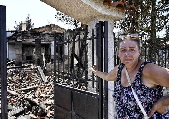 Una mujer, frente a su casa quemada después de un incendio forestal en el área de Agia Irini, en Grecia