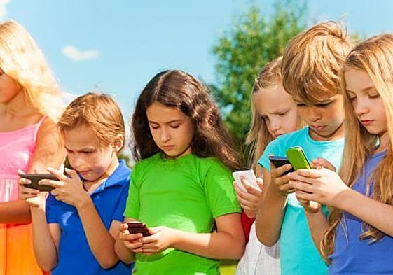Varios menores mirando móviles.