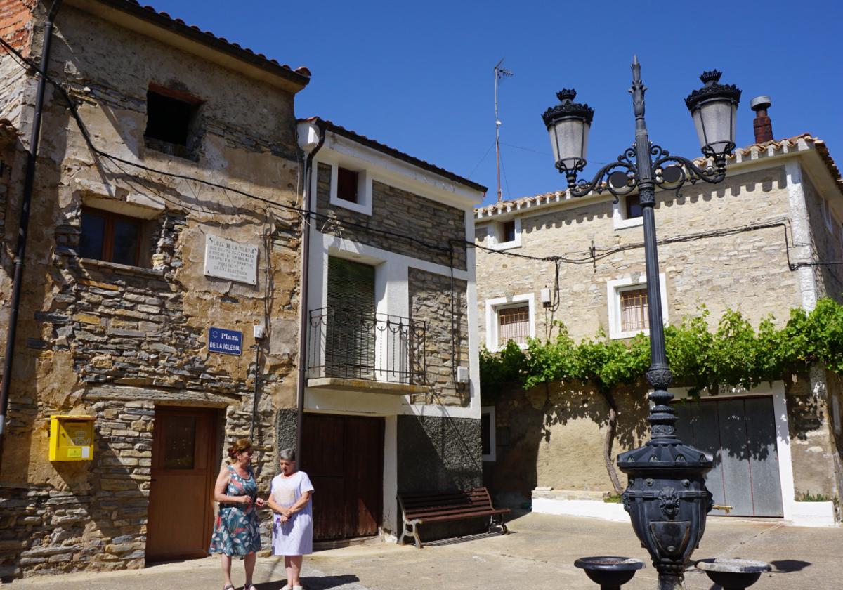 Dos vecinas conversan en la plaza de la iglesia de Valdeprado, donde un 85% del censo se encuentra fuera de España.