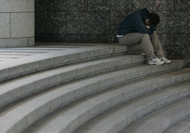 Joven con cabeza entre las piernas.