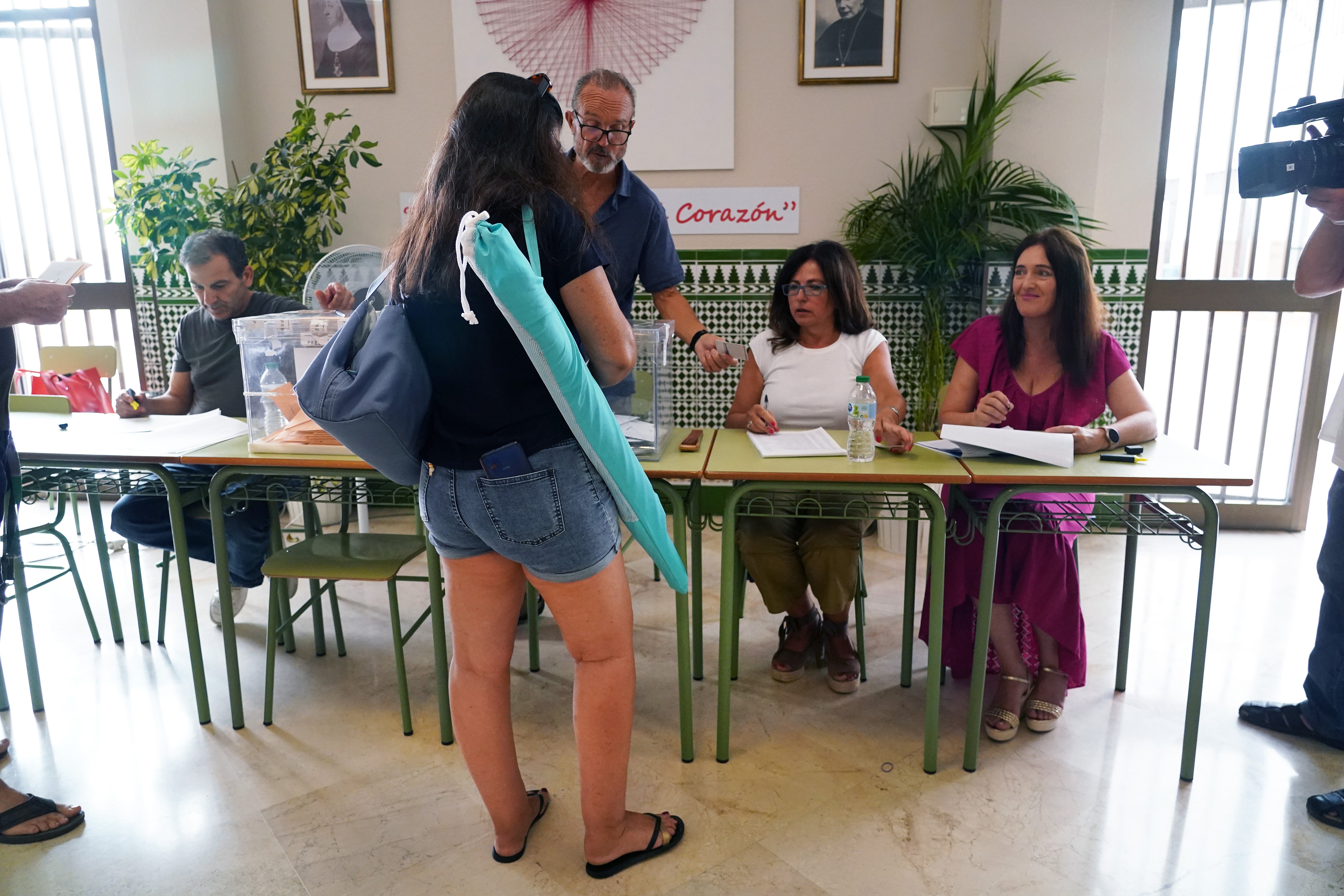 Varias personas con ropa de baño y utensilios de playa ejercen su derecho a voto durante las elecciones generales, en un colegio electoral, a 23 de julio de 2023, en Málaga