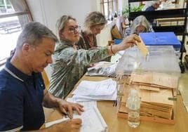 La presidenta de una mesa electoral de Oviedo deposita votos por correo en las urnas.