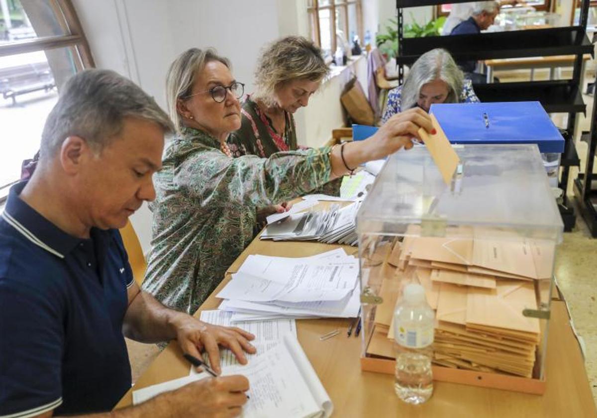 La presidenta de una mesa electoral de Oviedo deposita votos por correo en las urnas.