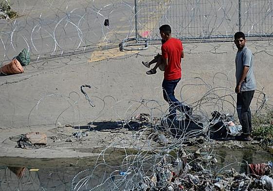 Migrantes cruzan las alambradas colocadas en el muro fronterizo para entregarse a las autoridades estadounidenses y pedir asilo.