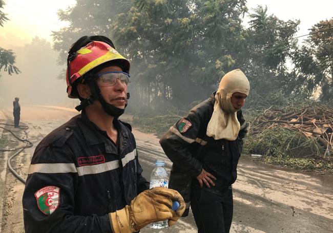 Dos bomberos en una de las áreas arrasadas por el fuego en Argelia.