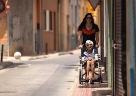 Una mujer traslada a una anciana el pasado 12 de julio, sobre las 14:00 horas en plena ola de calor.