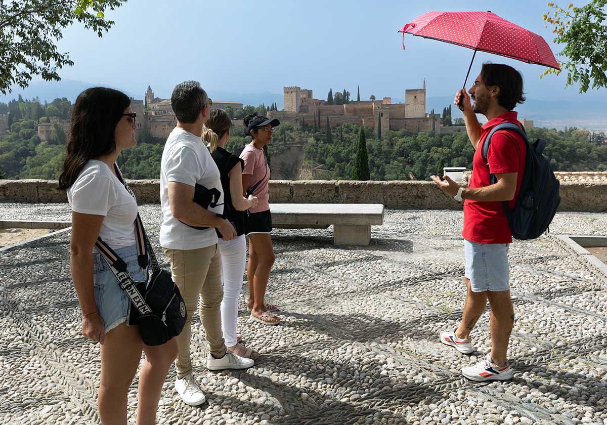 Un grupo de turistas atiende las explicaciones de un guía en el Mirador de San Nicolás de Granada.