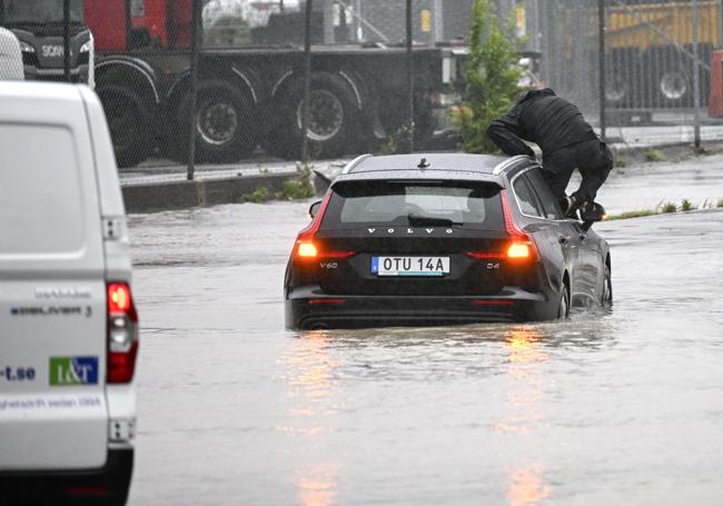 Un hombre sale de un coche sumergido en el agua debido a las inundaciones cerca de Malmo, en Suecia