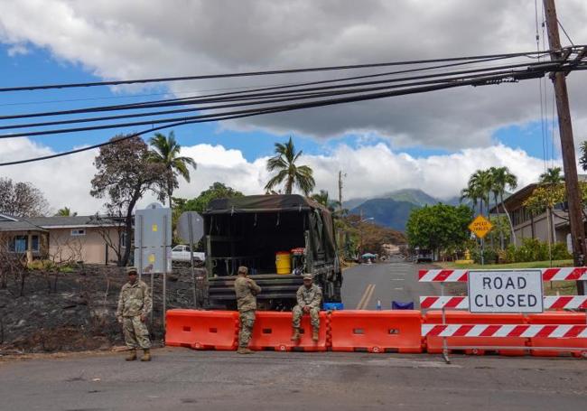 Tres militares vigilan uno de los accesos cerrados a la capital de la isla de Maui.