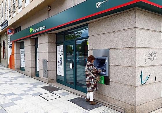 Una mujer saca dinero de un cajero.