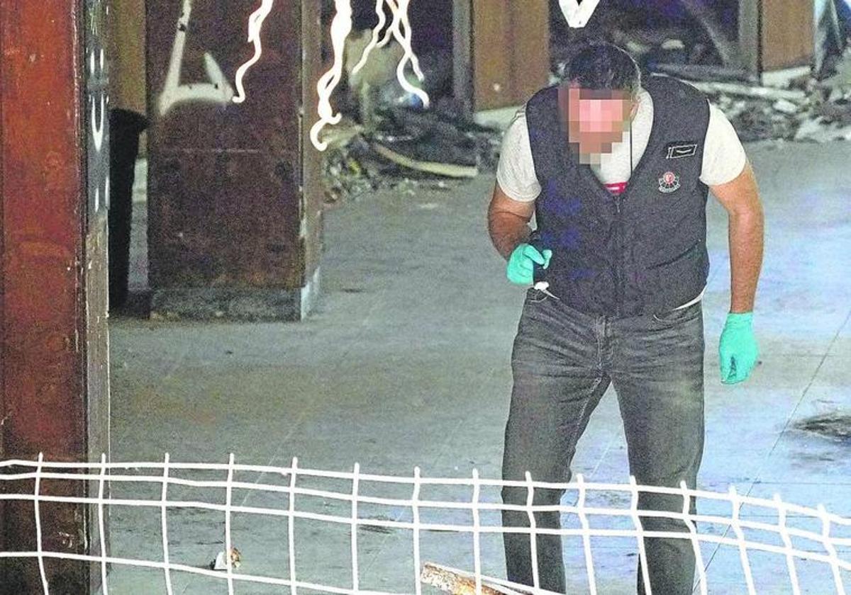 Un agente de la Ertzaintza busca pistas en el edificio donde se encontró el cadáver.